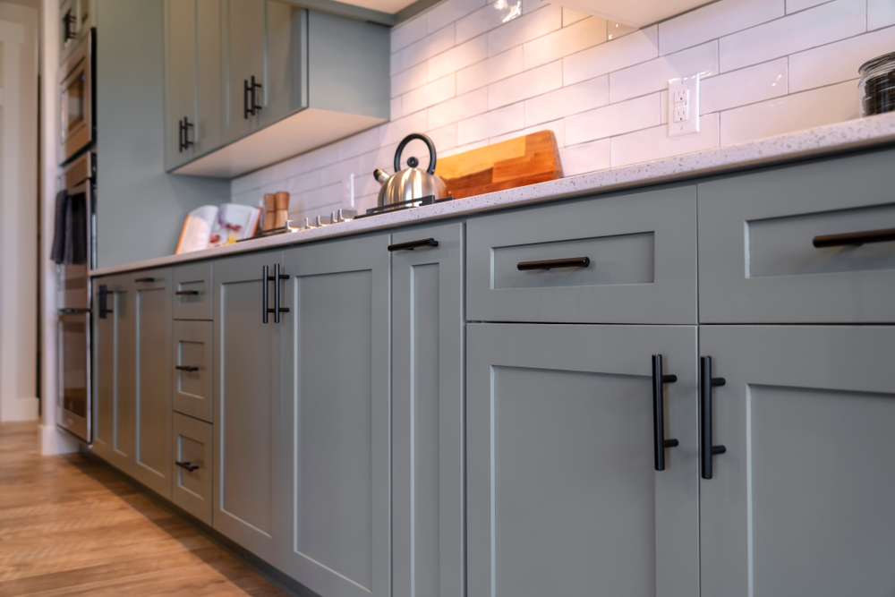 Refinished Kitchen cabinets with white countertop black handles and tile backsplash